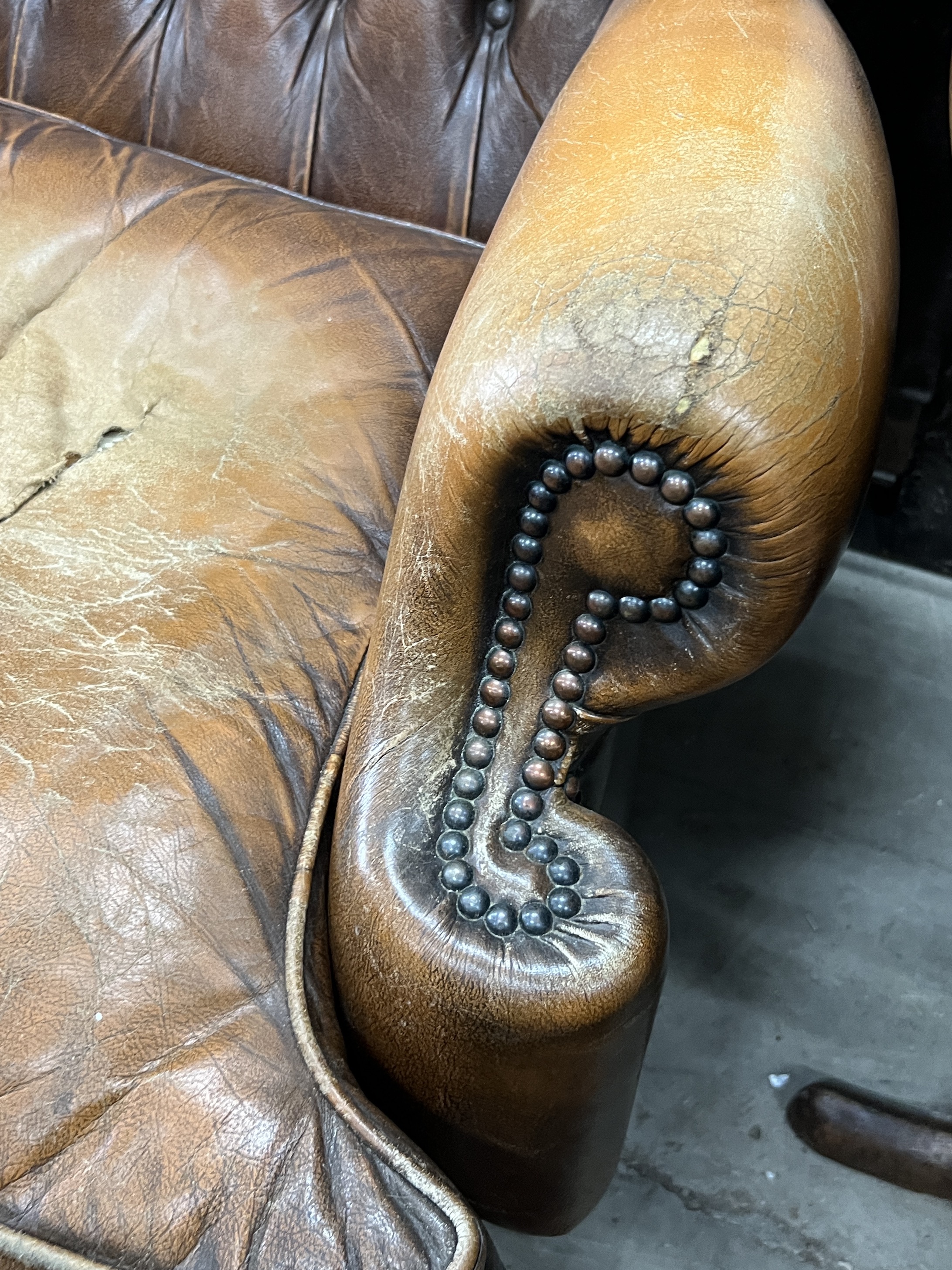 A Victorian style buttoned leather armchair, width 85cm, depth 76cm, height 106cm and a stool